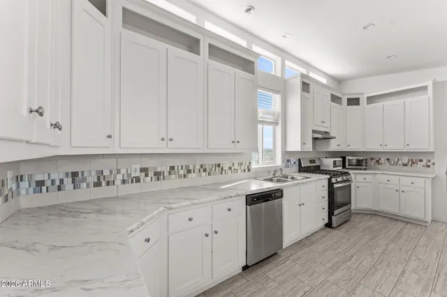 a kitchen with white cabinets sink and stove