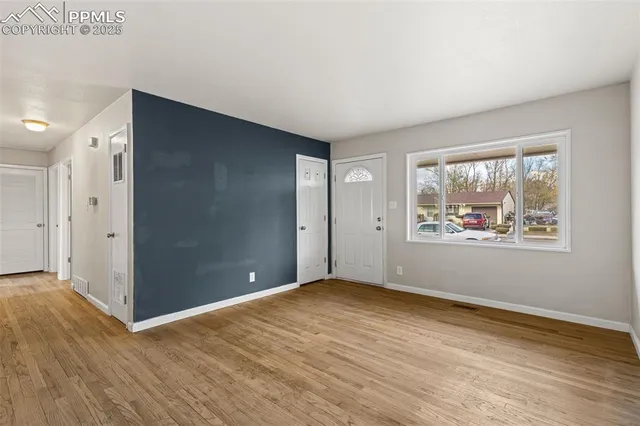 a view of an empty room with wooden floor and window