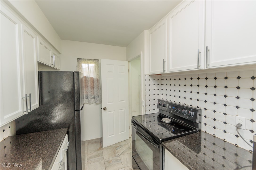 5445 Hauserman Road Cleveland, OH 44130 - Photo 18 of 45 Kitchen with black range with electric stovetop, white cabinets, light tile patterned floors, and tasteful backsplash