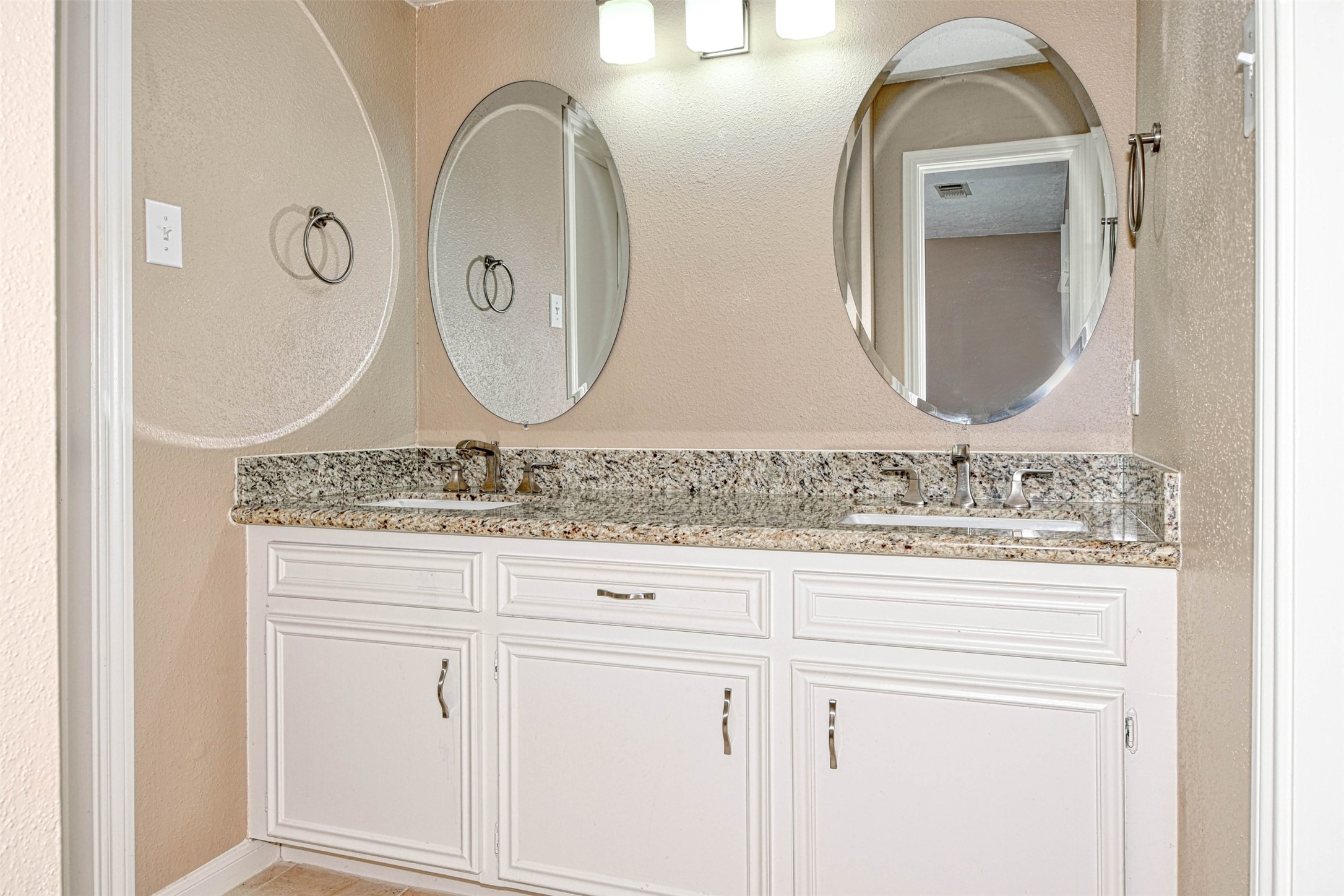 518 Moore Street Tomball, TX 77375 - Photo 12 of 18 Vanity area has dual sinks with granite counter tops, porcelain sinks, brushed nickel faucets, beveled mirrors, painted cabinets and brushed nickel hardware.