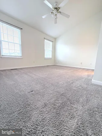 an empty room with a chandelier fan and windows