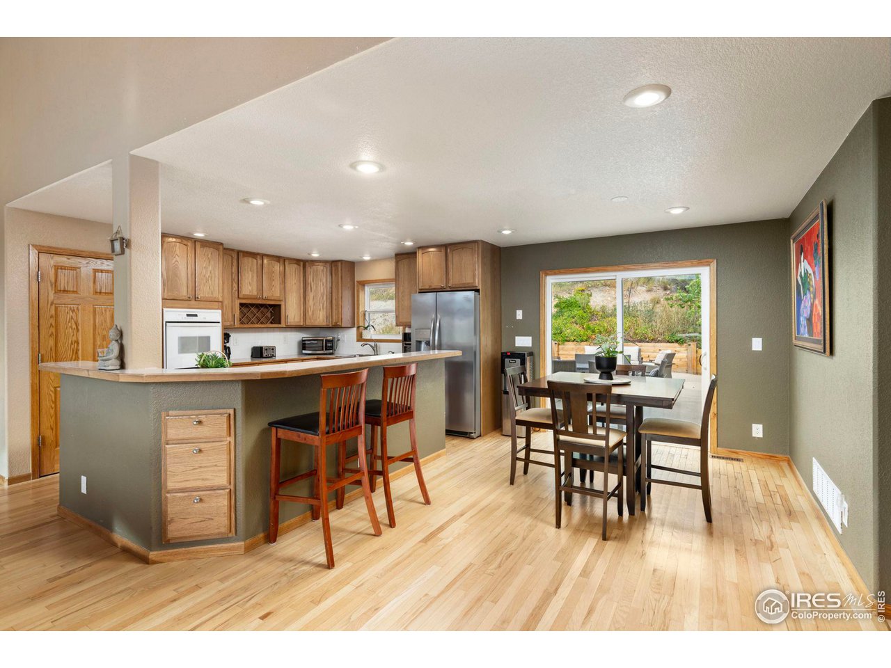 6586 Abaco Lane Berthoud, CO 80513 - Photo 9 of 40 a open kitchen with stainless steel appliances granite countertop a stove a refrigerator a kitchen island a dining table and chairs with wooden floor