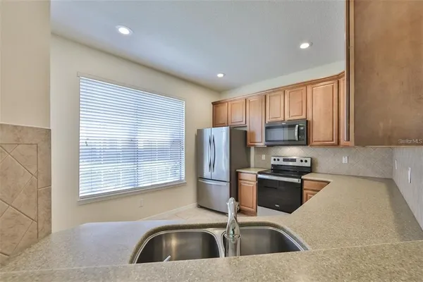 a kitchen with stainless steel appliances granite countertop a sink stove refrigerator and microwave