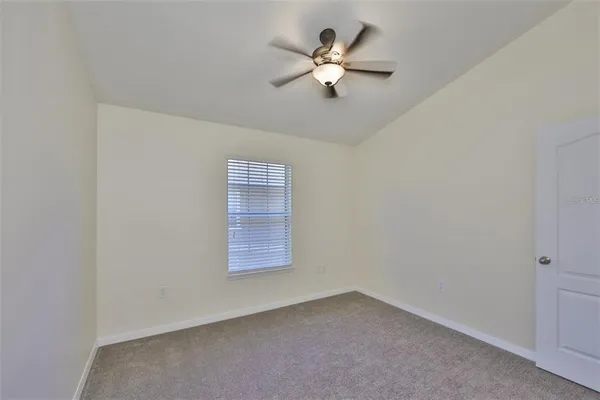 an empty room with a chandelier fan and windows