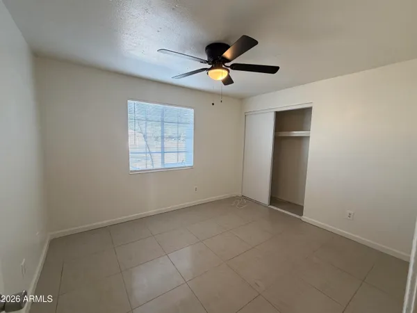 an empty room with a ceiling fan and window