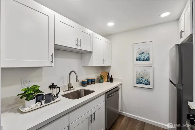 a kitchen with stainless steel appliances a sink a refrigerator and cabinets