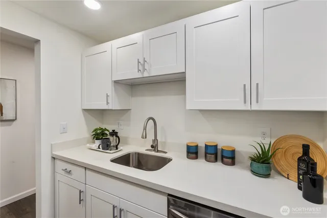 a kitchen with white cabinets a sink and dishwasher