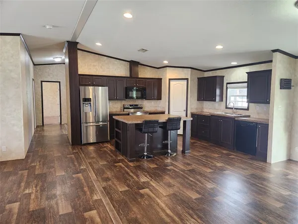 a kitchen with stainless steel appliances kitchen island granite countertop a refrigerator and a stove top oven