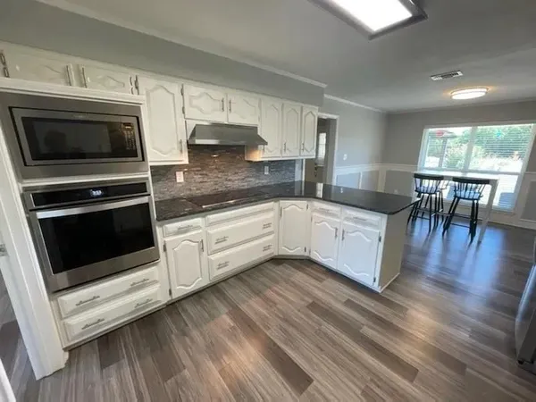 a kitchen with stainless steel appliances kitchen island granite countertop a stove a sink and white cabinets