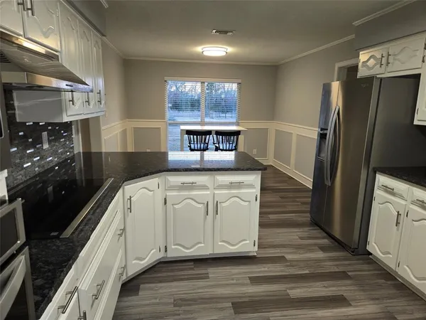 a kitchen with white cabinets and wooden floor