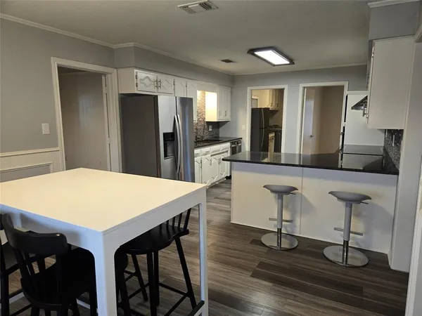 a kitchen with stainless steel appliances kitchen island granite countertop a dining table chairs and granite counter tops