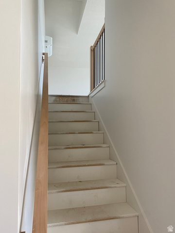 4676 West 75 North, Unit 401 West Point, UT 84015 - Photo 15 of 25 Staircase featuring a natural wood handrail, contrasting black metal balusters, and white risers