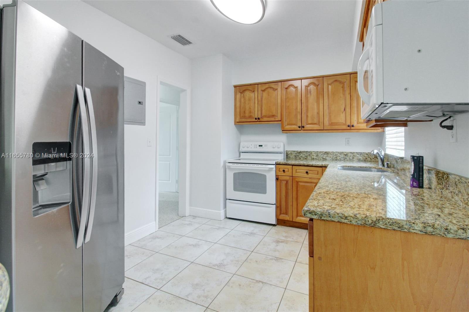 6990 Southwest 58th Street Miami, FL 33143 - Photo 8 of 11 a kitchen with stainless steel appliances granite countertop a refrigerator a stove and a sink