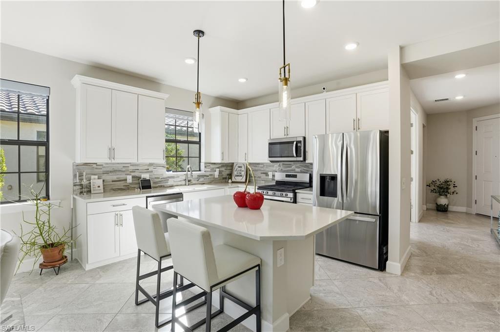 17377 Corsini Drive Fort Myers, FL 33913 - Photo 12 of 49 a kitchen with stainless steel appliances granite countertop a refrigerator a sink dishwasher a stove a dining table and chairs with wooden floor