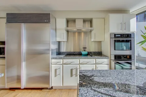 a kitchen with stainless steel appliances granite countertop a stove a sink and a refrigerator