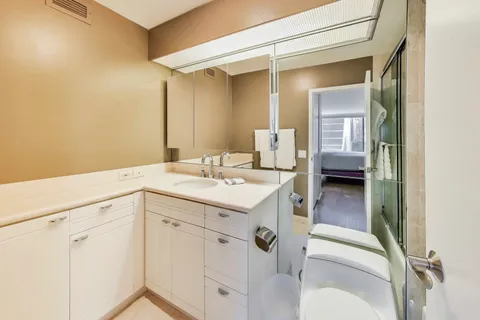 a bathroom with a sink a toilet and a large mirror