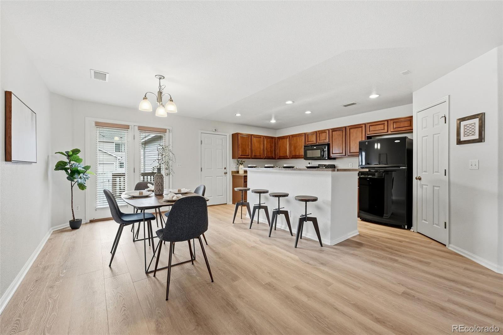 5811 Ceylon Street Denver, CO 80249 - Photo 12 of 43 a kitchen with stainless steel appliances kitchen island granite countertop a table chairs and a stove