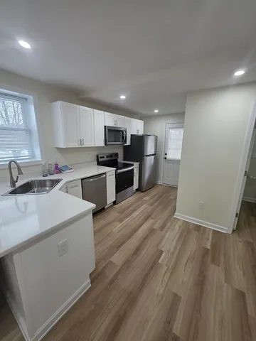 a kitchen with a sink wooden floor and stainless steel appliances