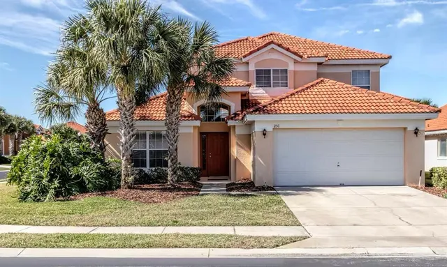 a view of a white house with a small yard and large tree