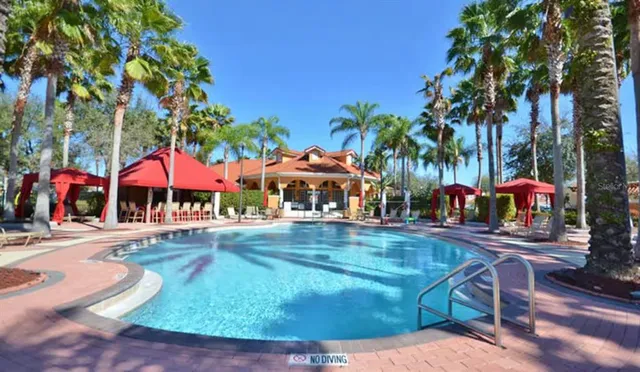 a view of swimming pool with a yard and palm trees