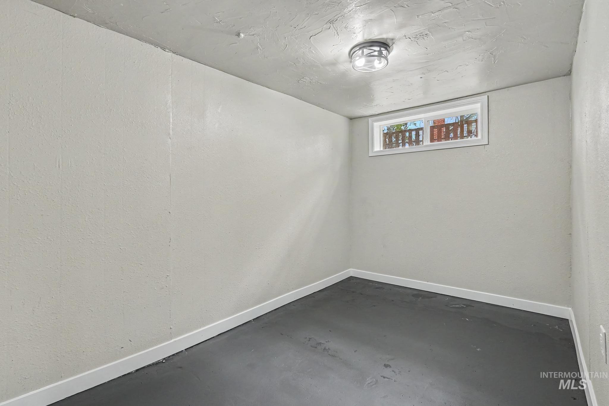 1023 State Street Weiser, ID 83672 - Photo 17 of 25 Room featuring light-colored walls, dark flooring, white baseboards, and a single ceiling light fixture