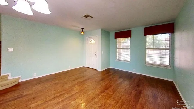 an empty room with wooden floor and windows