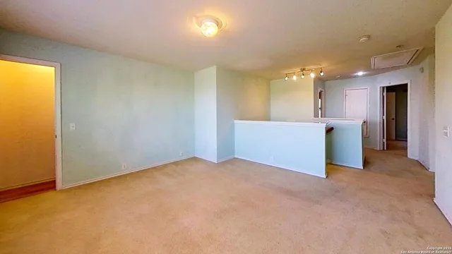 a view of an empty room with kitchen and a window