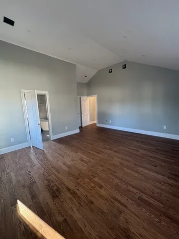 a view of an empty room with wooden floor and window
