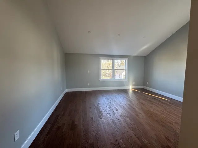 a view of an empty room with wooden floor and window