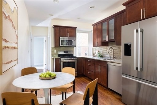 1898 Beacon Street, Unit 4 Brookline, MA 02445 - Photo 6 of 13 a kitchen with stainless steel appliances granite countertop a refrigerator a stove a sink a dining table and chairs