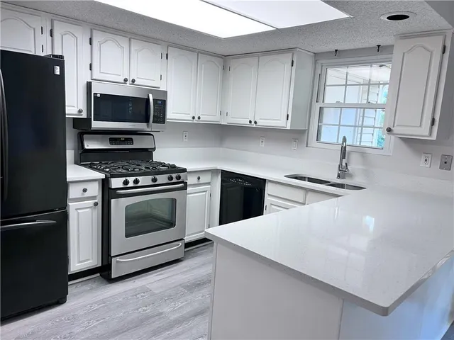 a kitchen with white cabinets and stainless steel appliances