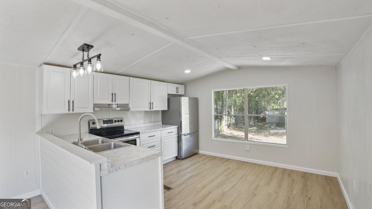 50 Sangster Road Jesup, GA 31545 - Photo 12 of 22 a kitchen with kitchen island white cabinets a stove a sink and a potted plant