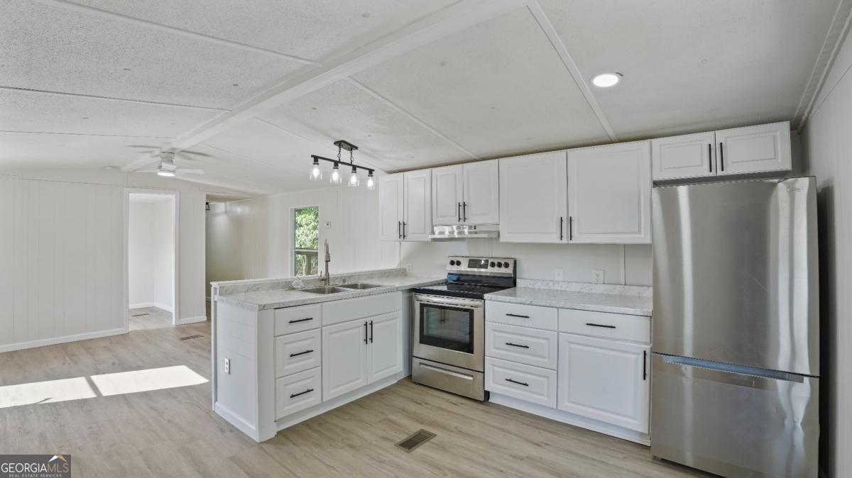 50 Sangster Road Jesup, GA 31545 - Photo 2 of 22 a kitchen with white cabinets stainless steel appliances and wooden floor