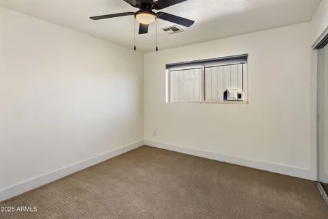 an empty room with a window and a fan