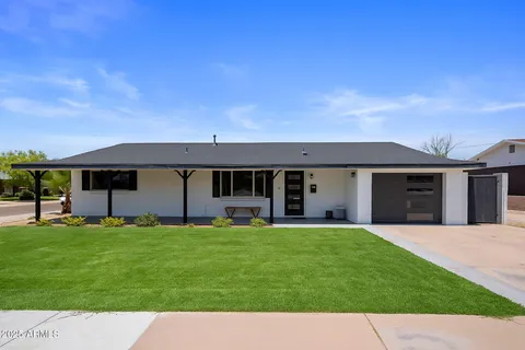 a view of a house with a yard and a large tree