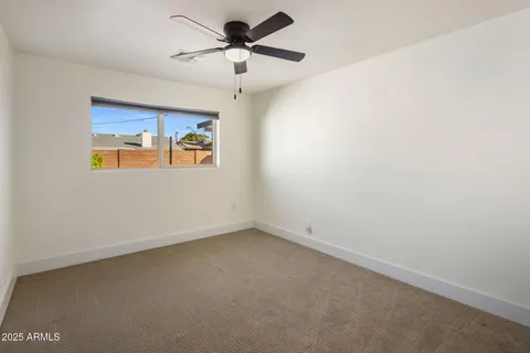 an empty room with a window and a ceiling fan