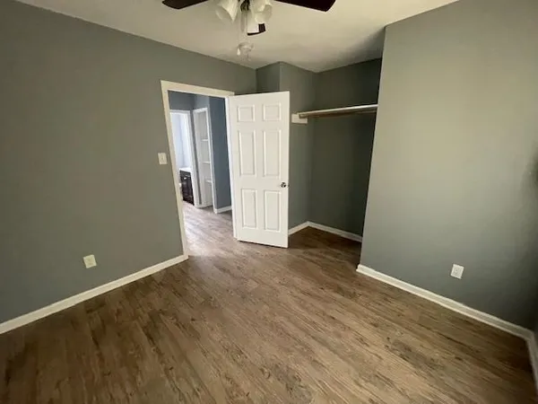 an empty room with wooden floor and a ceiling fan