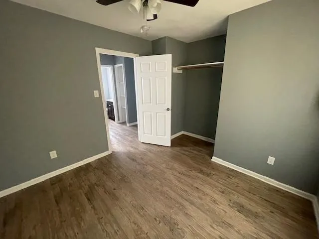 an empty room with wooden floor and a ceiling fan