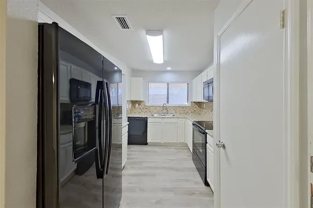 a kitchen with a refrigerator sink and cabinets