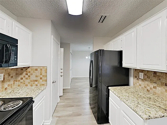 a kitchen with stainless steel appliances granite countertop a refrigerator a stove and a sink