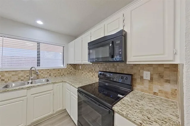 a kitchen with granite countertop a sink stove and microwave