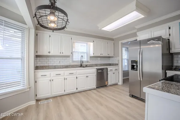 a kitchen with granite countertop stainless steel appliances a stove a refrigerator a sink and cabinets