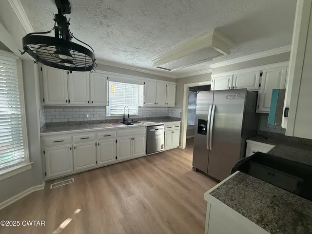 a kitchen with stainless steel appliances granite countertop a sink a stove a refrigerator and cabinets