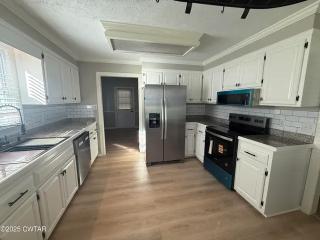 a kitchen with granite countertop a refrigerator stove top oven and sink
