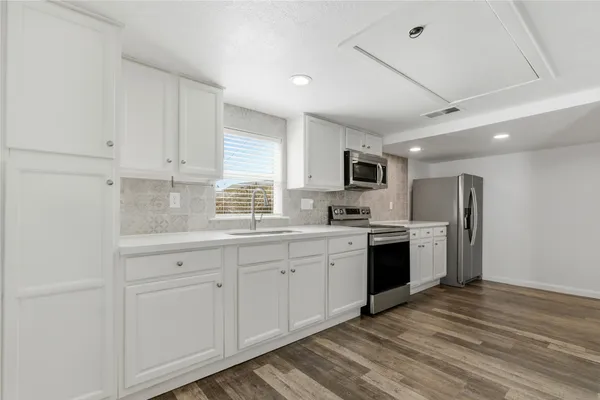 a kitchen with sink a refrigerator and white cabinets
