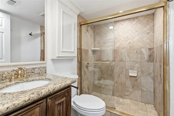 a bathroom with a granite countertop sink toilet and shower