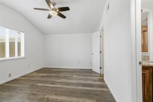a view of a room with wooden floor and a ceiling fan