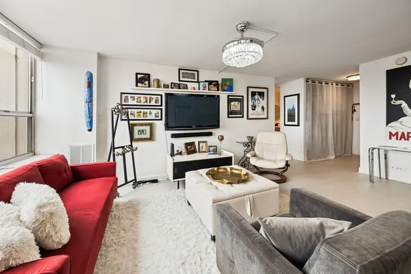 a living room with furniture and a flat screen tv with kitchen view