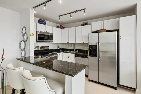 a kitchen with kitchen island a counter top space a sink stainless steel appliances and cabinets
