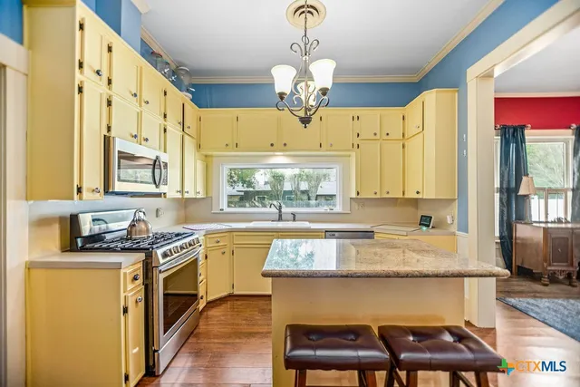 a kitchen with stainless steel appliances granite countertop a stove a sink dishwasher and cabinets with wooden floor